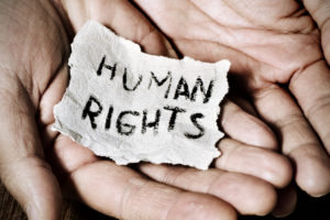 Två händer som håller en papperslapp med texten human rights.
