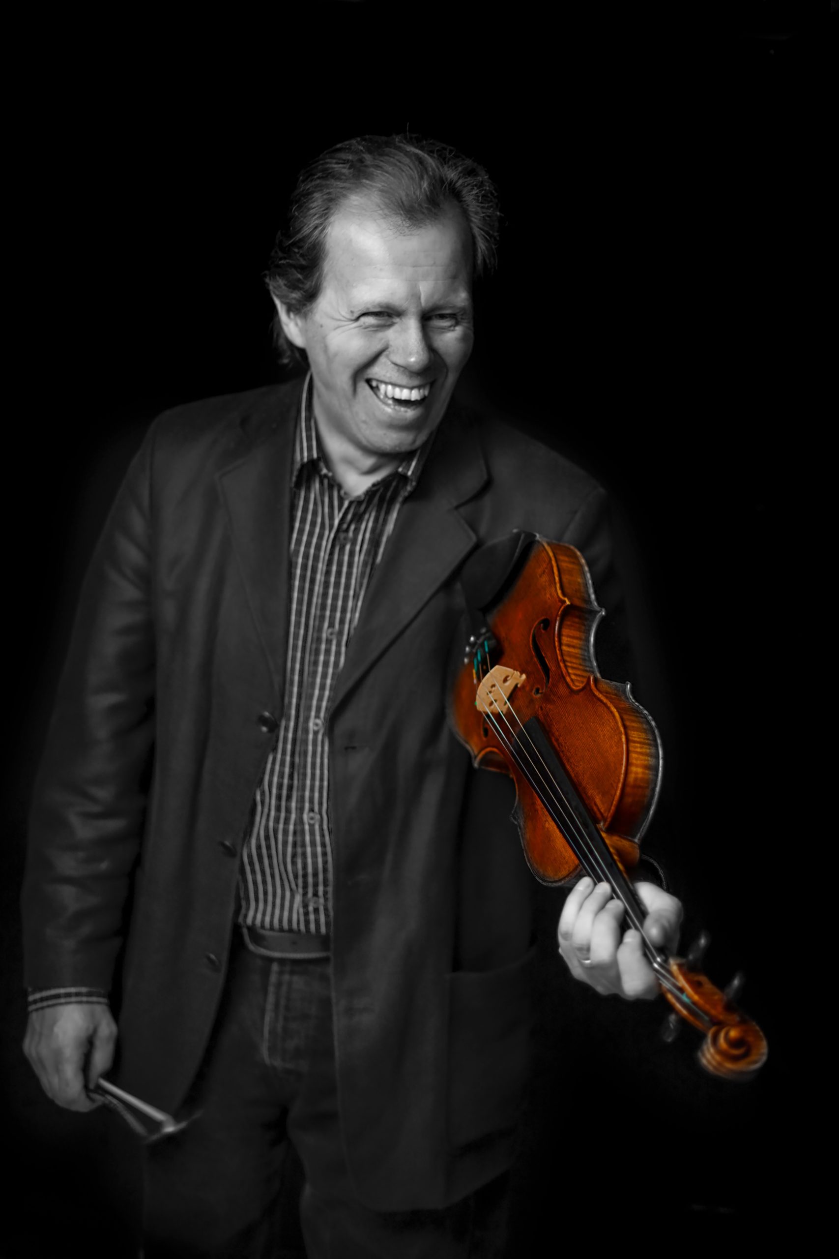 På bilden syns berättaren och spelmannen Thomas Andersson. Thomas ler samtidigt som han håller en fiol i vänster hand och en stråke i höger hand.